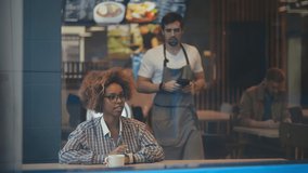 African-american young female customer keeping her wrist over electronic payment machine while paying for order through smartwatch in cafe. Waiter holding terminal while client paying with smartwatch - Powered by Shutterstock - Get 15% off with code: PIKWIZARD15