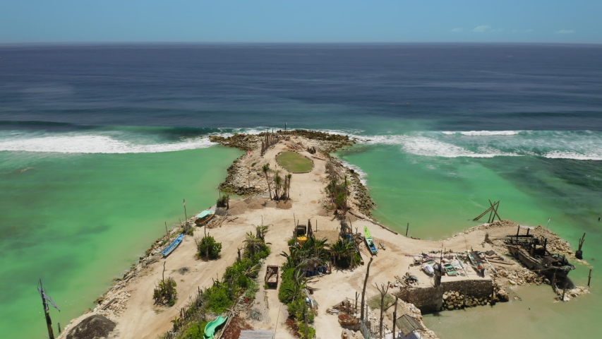 Aerial drone flight over land, Bali, Indonesia, 4k. New sand spit with constuction site of some buildings. Fantastic view at indian ocean. At sunny day water looks emerald green bright