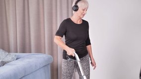 woman using vacuum cleaner listen to music and dancing with headphones