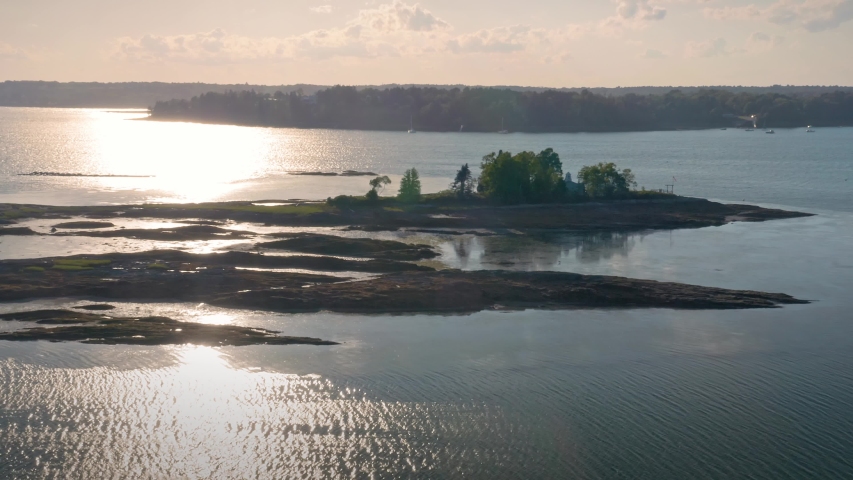 Aerial: Flying over a harbor & island at sunset. Orr