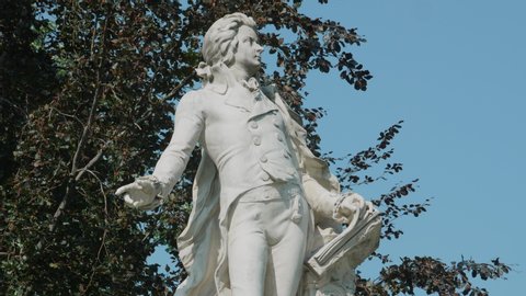 VIENNA AUSTRIA AUG. 22. 2019 Wolfgang Amadeus Mozart monument, tripod shot of Mozart memorial tourist attraction city center Vienna, close up of the statue, background tree with blue sky