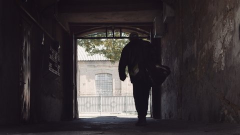 Man with duffel bag walks through dark tunnel in slow motion red helium 8K
