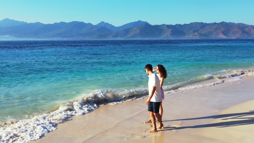Husband And Wife In Their Honeymoon In Spain Enjoying The Waves While Talking About Their Sweet Moments - Wide Shot
