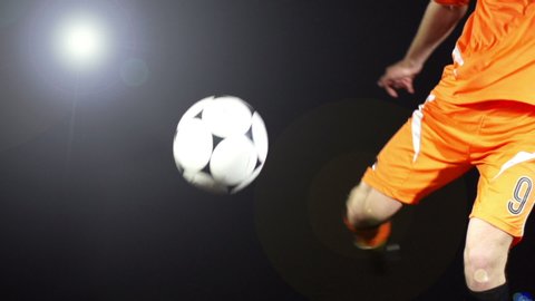 Football /Soccer player kicking an unbranded ball. The Footballer volleys the ball in Super Slow motion. Black Background