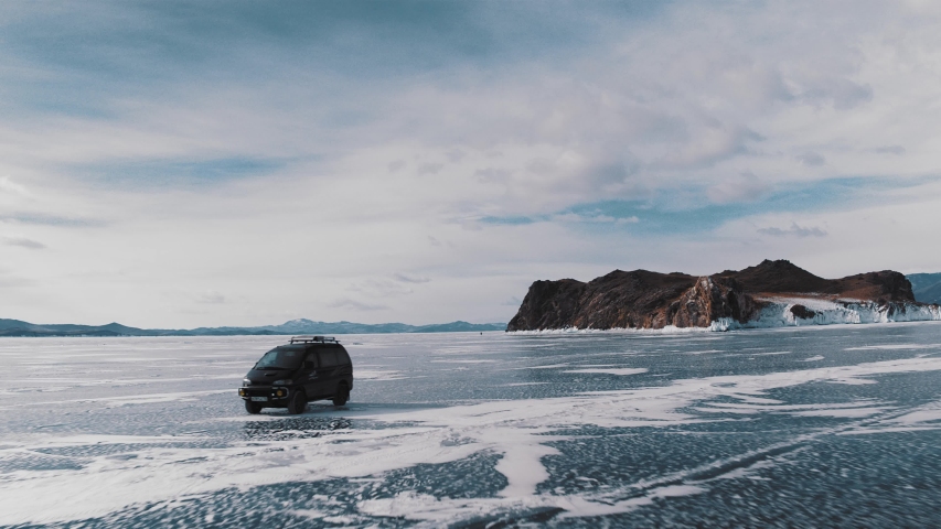 Car on frozen Lake Baikal winter landscape with clear smooth ice, Aerial view.