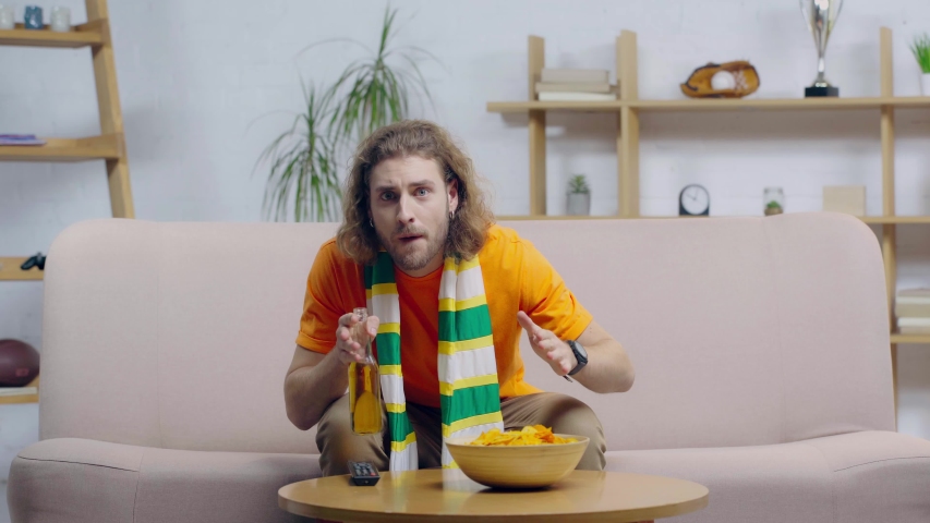 worried sport fan with crossed fingers watching championship