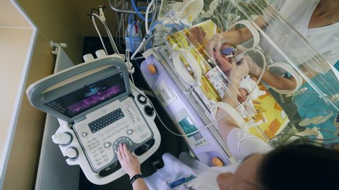 A baby in the incubator in undergoing an ultrasonic scan