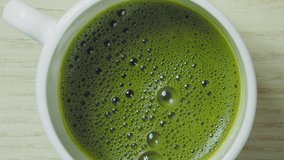 Pouring milk into green matcha tea, slow motion video