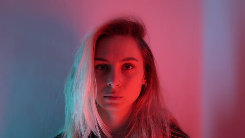Close Up Portrait of Young Blondy Girl witn Nose ring at Neon Lighting Colors Background. Beauty woman look at camera happy mood