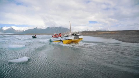 Jokulsarlon Glacier Lagoon, Iceland. April, 2018. Amphibian boat tour in Iceland. Tourists suited up in weather- and wind-resistant red over-suits and life jackets.