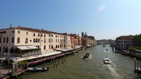 Venice / Veneto / Italy - June 24, 2019: Grand Canal with boats at sunny day, Venice, Italy. San Geremia church dome with ancient Romanesque bell tower and Palazzo Labia on Grand Canal Venice, Italy.