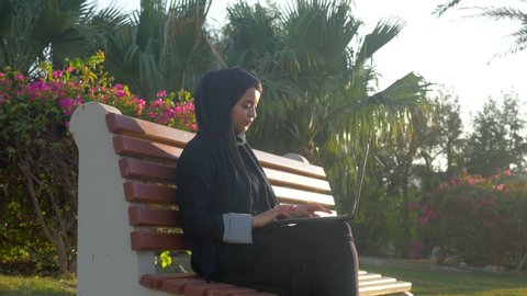 Muslim woman wearing an abaya and using Laptop .The abaya or abaya is a black cloth worn by Muslim women in some regions of the Middle East, especially in the Arab Gulf countries.