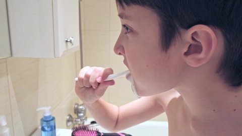 A portrait of a caucasian teen boy brushing teeth in bathroom, close up.