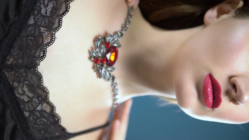 beautiful young girl wears a necklace. blue background. vertically.