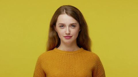 Childish disobedient behavior. Playful young woman with brown hair in pullover sticking out tongue at camera, teasing with naughty foolish expression. indoor studio shot isolated on yellow background
