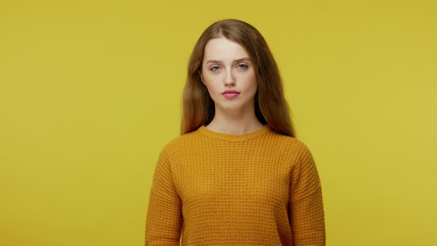 Thoughtful pretty girl with brown hair in pullover rubbing her chin and looking aside with pensive expression. pondering a solution, doubting question. indoor studio shot isolated on yellow background | Shutterstock HD Video #1045280530