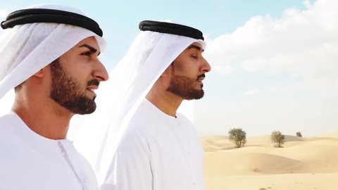 Two men with emirates white kandura traditional outfit making safari in the desert of Dubai