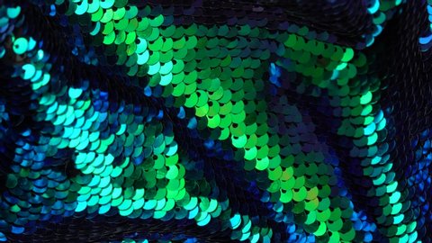 Fabric sequins green and blue colors. Holiday abstract glitter background with blinking lights. Fashion luxury fabric glitter, spangles, paillettes