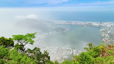 Aerial timelapse of Ipanema in Rio de Janeiro, Brazil. View of the city and Lagoa lake with dense cloud cover rolling and blocking the view. Moutains and hills in the background.