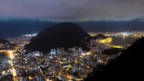 Aerial night timelapse of Botafogo and Ipanema skyline in Rio de Janeiro city, Brazil. View of city buildings with traffic and light. Ocean shoreline and hills and mountain in the back  