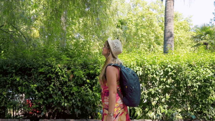Young woman walking down the road, surrounded by green trees and bushes