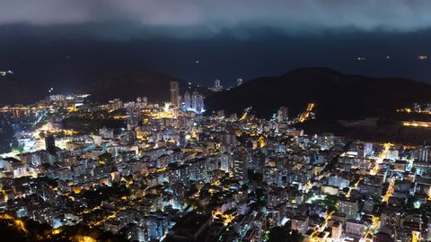 Aerial night timelapse of Botafogo and Copacabana skyline in Rio de Janeiro city, Brazil. View of city buildings with traffic and light. Ocean shoreline and hills and mountain in the back 