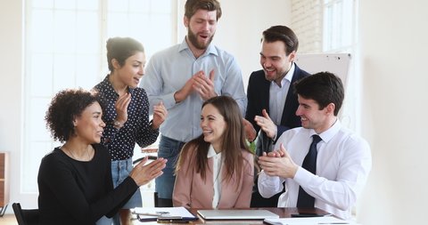 Friendly multiethnic business team coworkers congratulate happy proud best female leader winner applaud in office, diverse employees group praise colleague for professional achievement reward concept