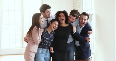 Overjoyed ecstatic friendly professional multiracial team business people group bonding celebrating triumph good teamwork result success together standing in office, rewards and achievements concept