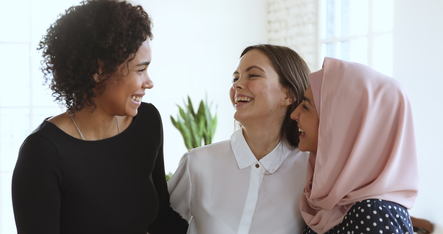 3 cheerful friendly diverse millennial women bonding laughing looking at camera, three happy young ladies having fun embracing in office, closeup portrait, multicultural unity friendship concept | Shutterstock HD Video #1045309147