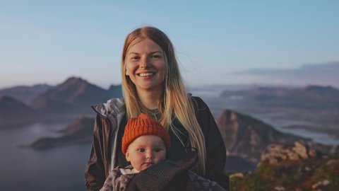 Mother with baby daughter traveling family vacations in Norway hiking together active healthy lifestyle happy smiling woman and child outdoor happy emotions Lofoten islands landscape