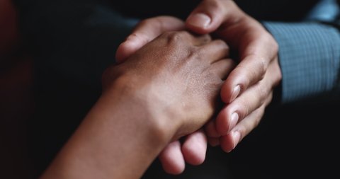 Close up young african american man holding female hands, demonstrating support. Mixed race spouses reconciling after misunderstanding. Biracial husband comforting wife, overcoming problems together.