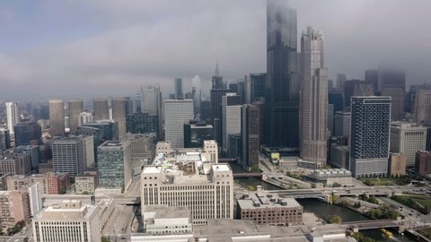 Aerial shot above Chicago Downtown with fog above top of the skyscrapers. Highway with cars leading to the city center