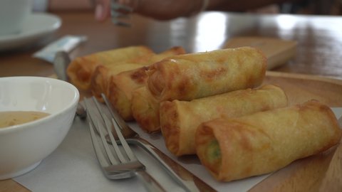Fried Spring Rolls with dipping sauce on a wooden dish.