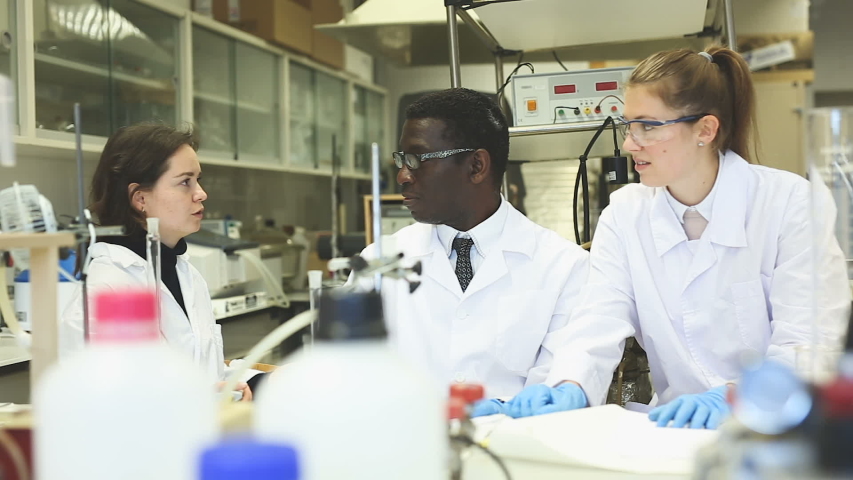 Portrait of proffesional male and female lab technicians with different test tubes
