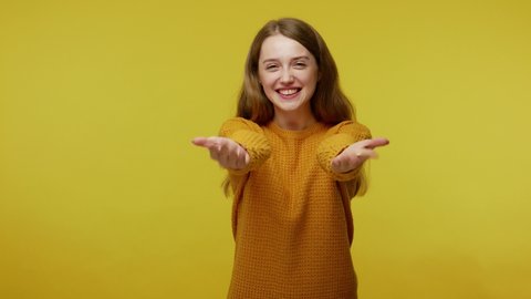 Come into my arms. Adorable happy girl with brown hair in pullover gesturing come here for free hugs and smiling sincerely with welcoming expression. indoor studio shot isolated on yellow background