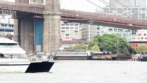 NEW YORK, NEW YORK/USA - JUNE 17, 2015: A Seastreak ferry on the East River under the Brooklyn Bridge. People can be seen.