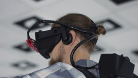 Close up tracking arc 360 degree shot of a young man wearing virtual reality headset and making hand gestures
