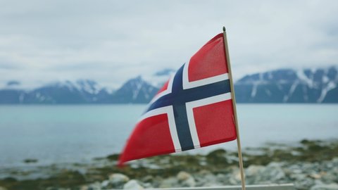 Flag of Norway in the wind with mountains and fjord landscape norwegian country national symbol Lyngenfjord view