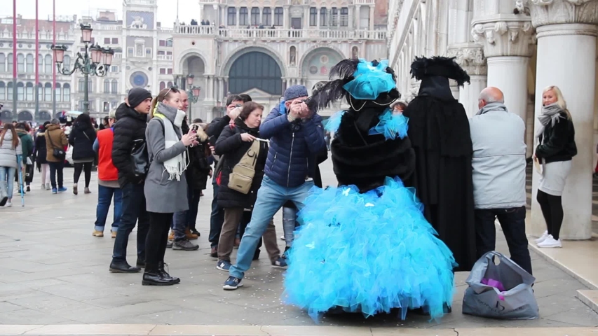 Venice, Italy - January 28, 2018. Tourists photographing a Venetian couple with masks during the great Carnival of Venice.