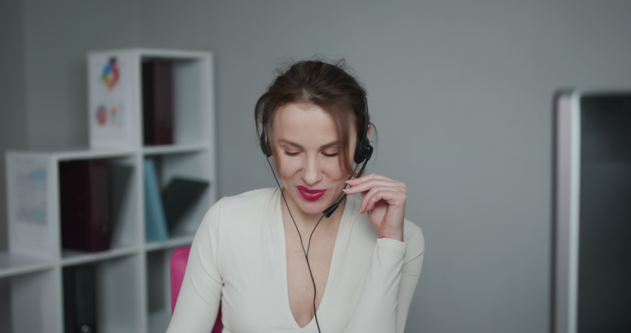 Attractive young female customer service agent talking to a customer with a telephony headset. Royalty-Free Stock Footage #1045353073