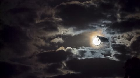 Shot of a bright full moon among moving clouds.