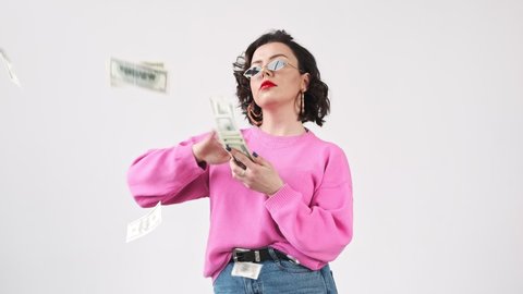 Rich chic woman, stylish fashion blogger, throwing money, scatter the dollars, spending money on useless thing.  