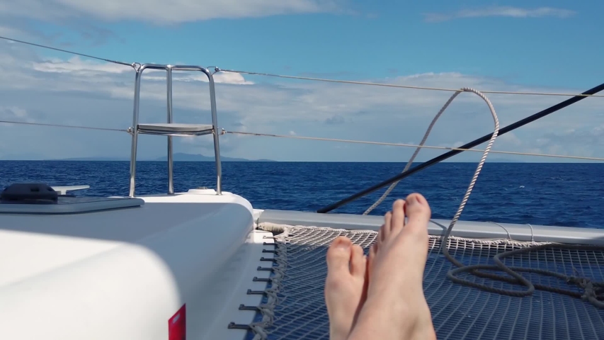 View from the sailboat on the landcape with person`s feet in foreground - closeup on feet