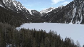 Aerial Drone footage winter view of Fedaia Dam lake with snow in Dolomites Alps Italy // no video editing