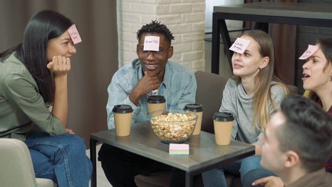 Diverse group of friends playing "Who am I" game with sticky papers attached to foreheads. Friendship, leisure and entertainment concept