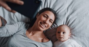 Authentic close up of neo mother and her newborn baby making a selfie or video call to father or relatives in a bed. Shot in 8K. Concept of technology, new generation,family, connection, parenthood