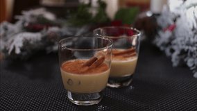 A slow push in into two glasses of holiday drink Christmas eggnog garnished with cinnamon sticks - Powered by Shutterstock - Get 15% off with code: PIKWIZARD15