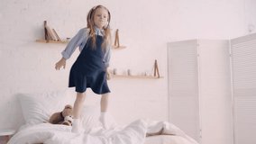 Kid in headphones jumping on bed