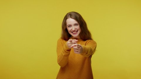 Hey you! Glad happy girl with brown hair in pullover smiling excitedly and pointing to camera, beauty choosing lucky winner, indicating to awesome you. indoor studio shot isolated on yellow background