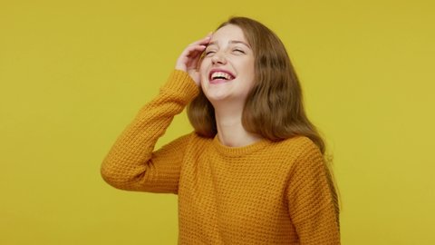 Sincere laughter. Good-natured joyful happy girl with brown hair in pullover laughing out loudly, amused by funny joke, enjoying positive emotions. indoor studio shot isolated on yellow background
